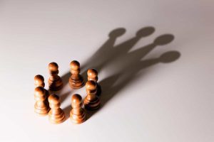 Image with several chess pieces with a shadow forming a crown