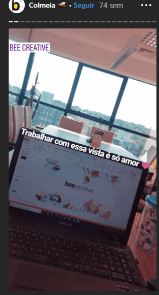 Story da Bee. Alt text: Example of stories from Bee Creative's Instagram. A computer and, in front, the window with a view of the city of Campinas. Quote: Working with this view is pure love!